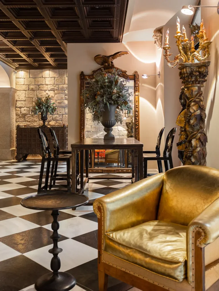 zona de estar con sillon dorado mesa de madera y espejo ornamental